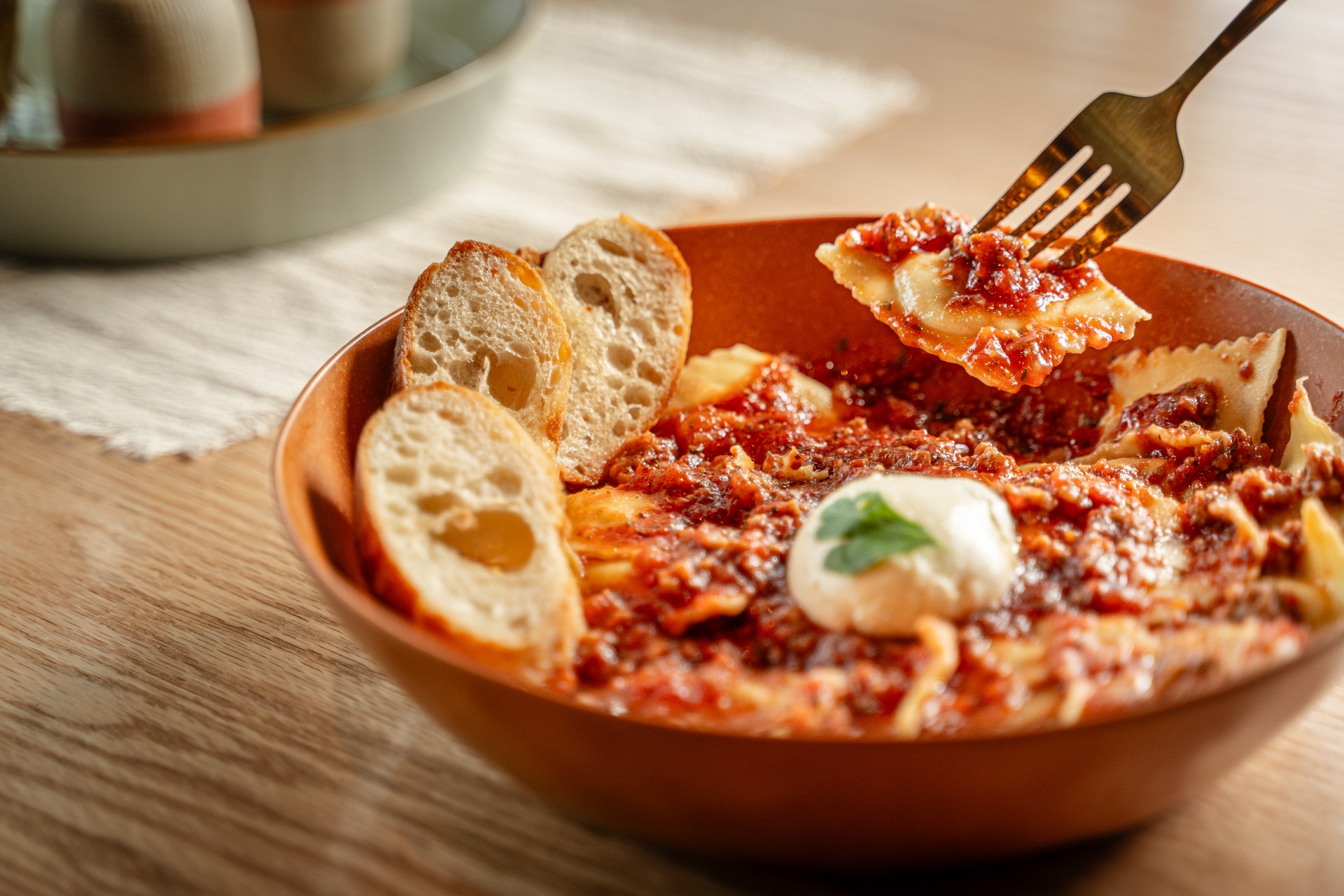 Handmade ravioli in rich red meat sauce with toasted bread and a dollop of ricotta at Biada Ravioli Kitchen in Logan, Utah